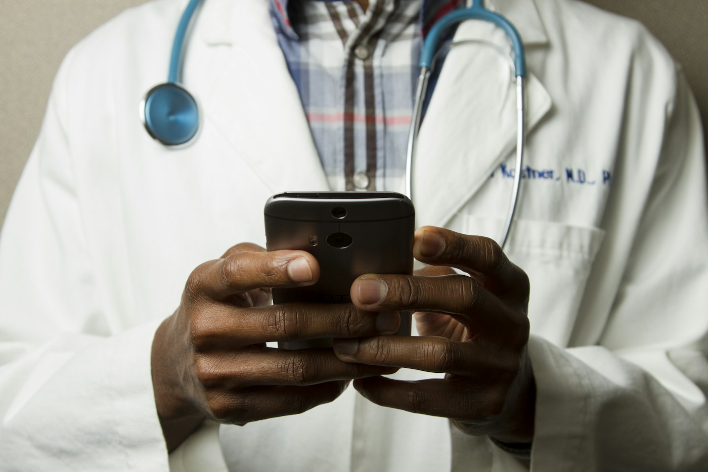 Healthcare professional using a mobile device with a stethoscope around their neck